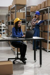 Warehouse employee doing goods supply chain management on laptop