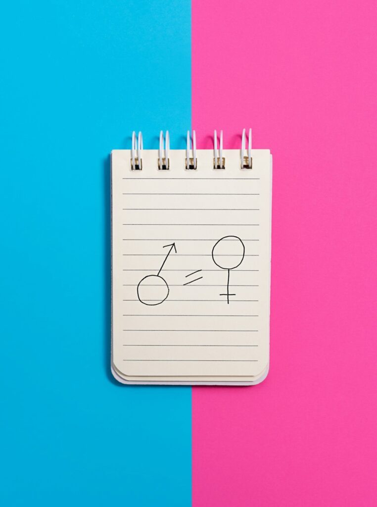 The concept of gender equality. Notebook with female and male symbols on a blue and pink background