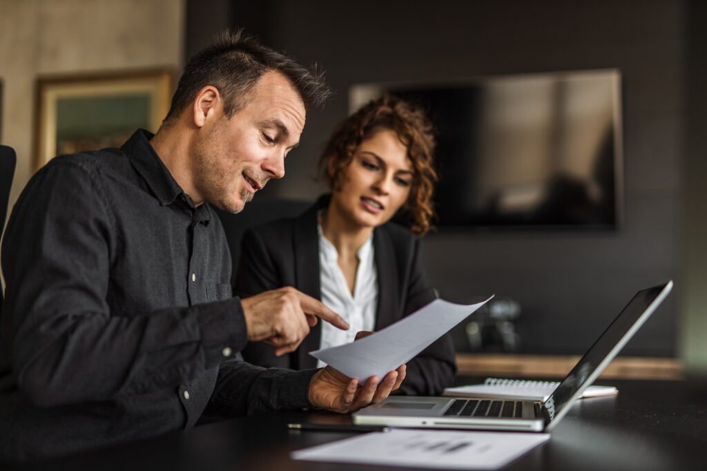 Two persons at work, having business plan.