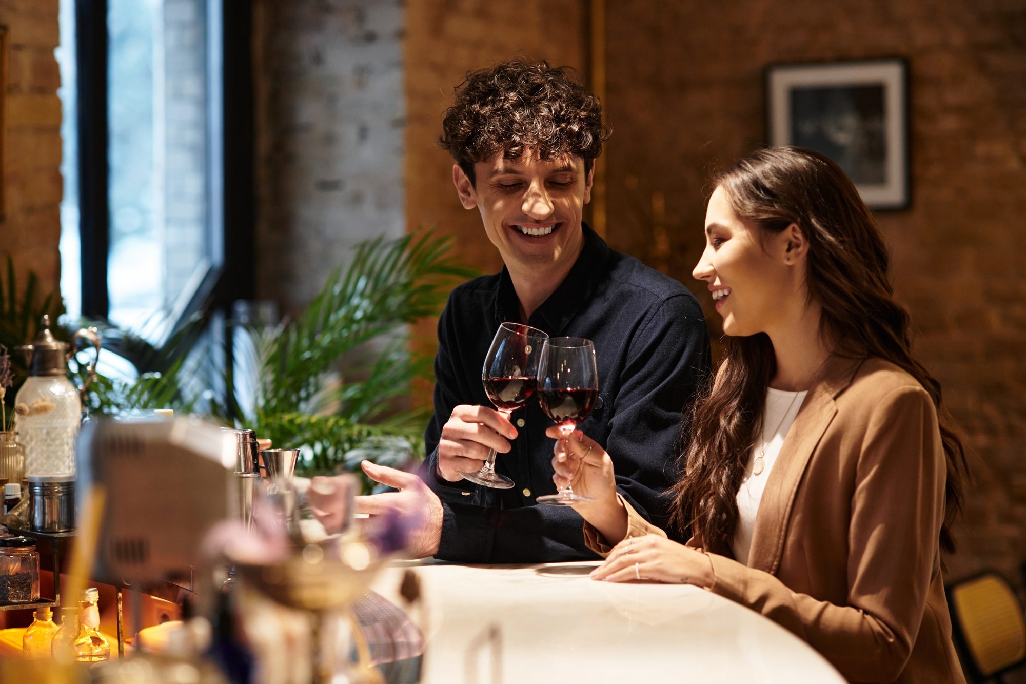 Young couple celebrates their love with cheers and laughter at a restaurant bar on Valentines Day.