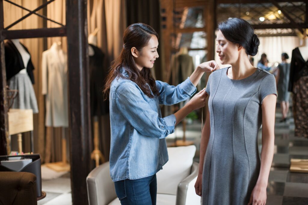 Fashion designer taking measurement of customer