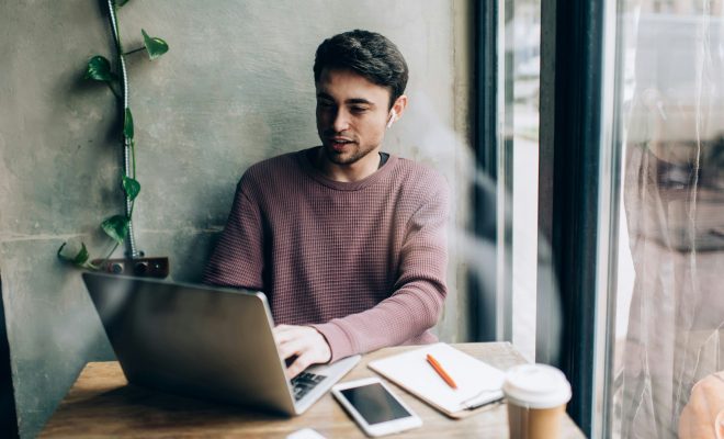 Caucasian blogger in bluetooth headphones browsing web publication