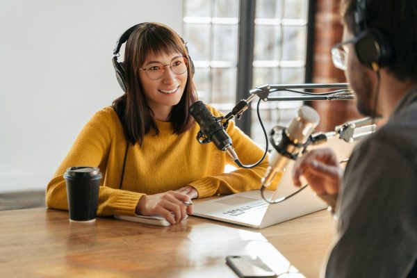 Man and woman podcasters interview each other for audio podcast in studio