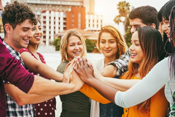 Young happy people stacking hands outdoor - Focus on hands